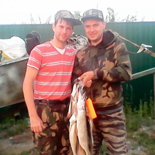 Рыбаки и пойманная ими щука на территории дома рыбака Кордон